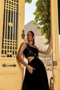 Woman in a black outfit standing in front of a yellow door with a scenic background Clep