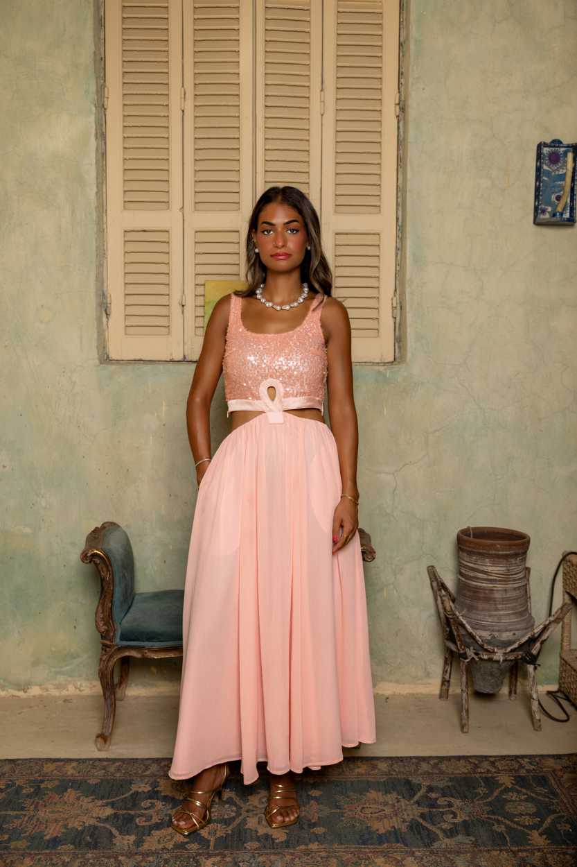 Woman in a pink dress standing in a room with vintage decor. Clep