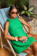 Woman in a green dress sitting on a striped chair outdoors. Clep