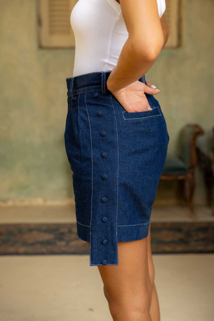 Person wearing a blue denim skirt with buttons in an indoor setting Clep