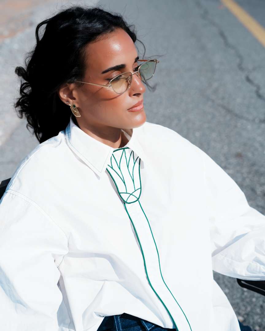 Woman wearing a white shirt with green design outdoors Clep