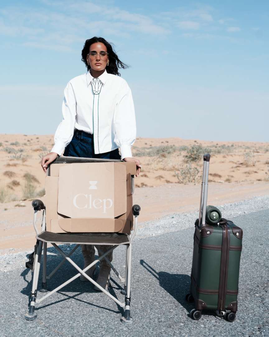 Person holding a Clep box with a suitcase next to them in a desert setting Clep