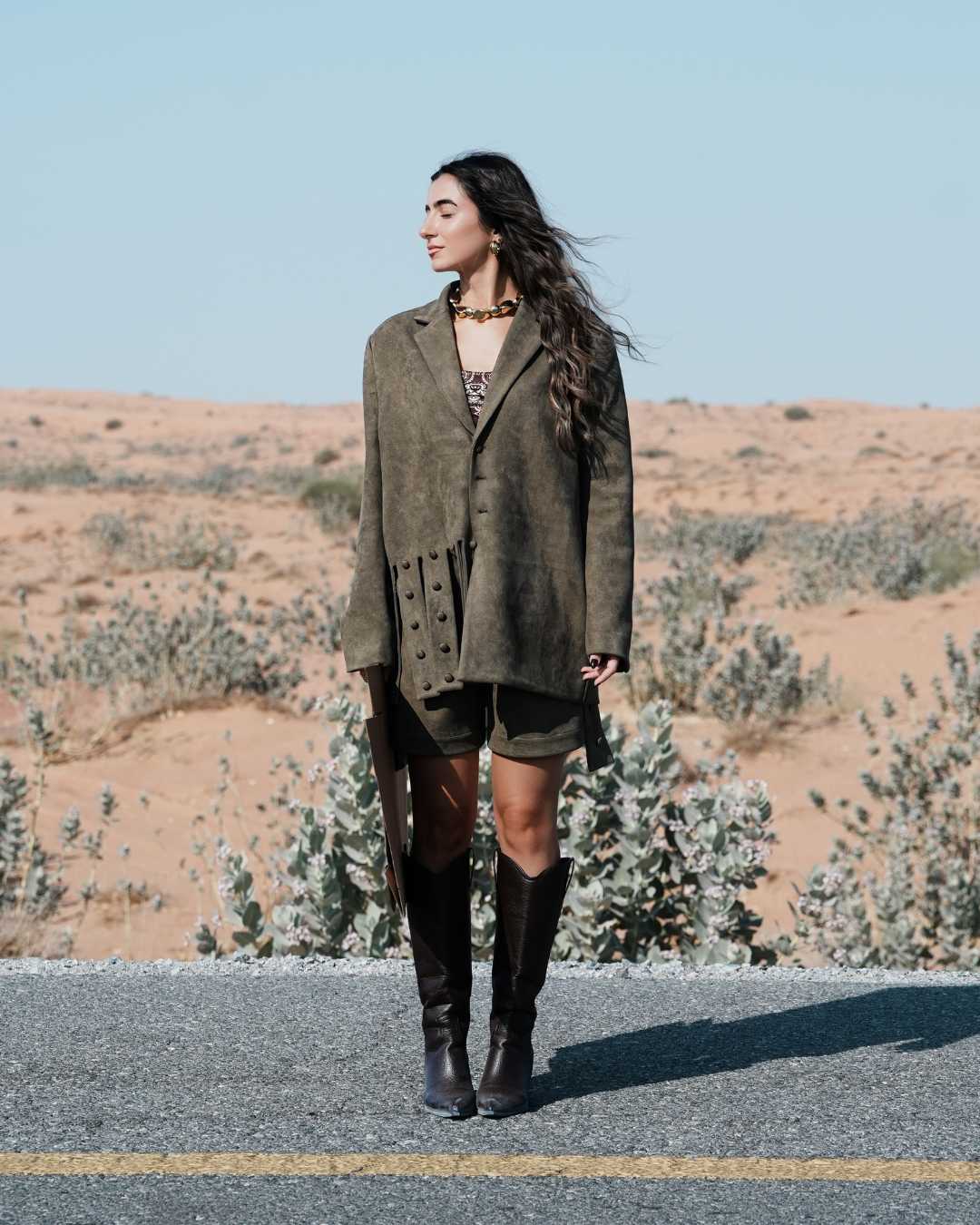 Woman standing on a road with a desert landscape in the background Clep