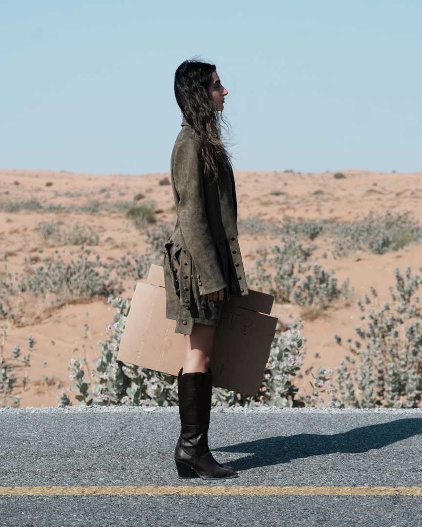 Person walking on a road with a desert landscape in the background