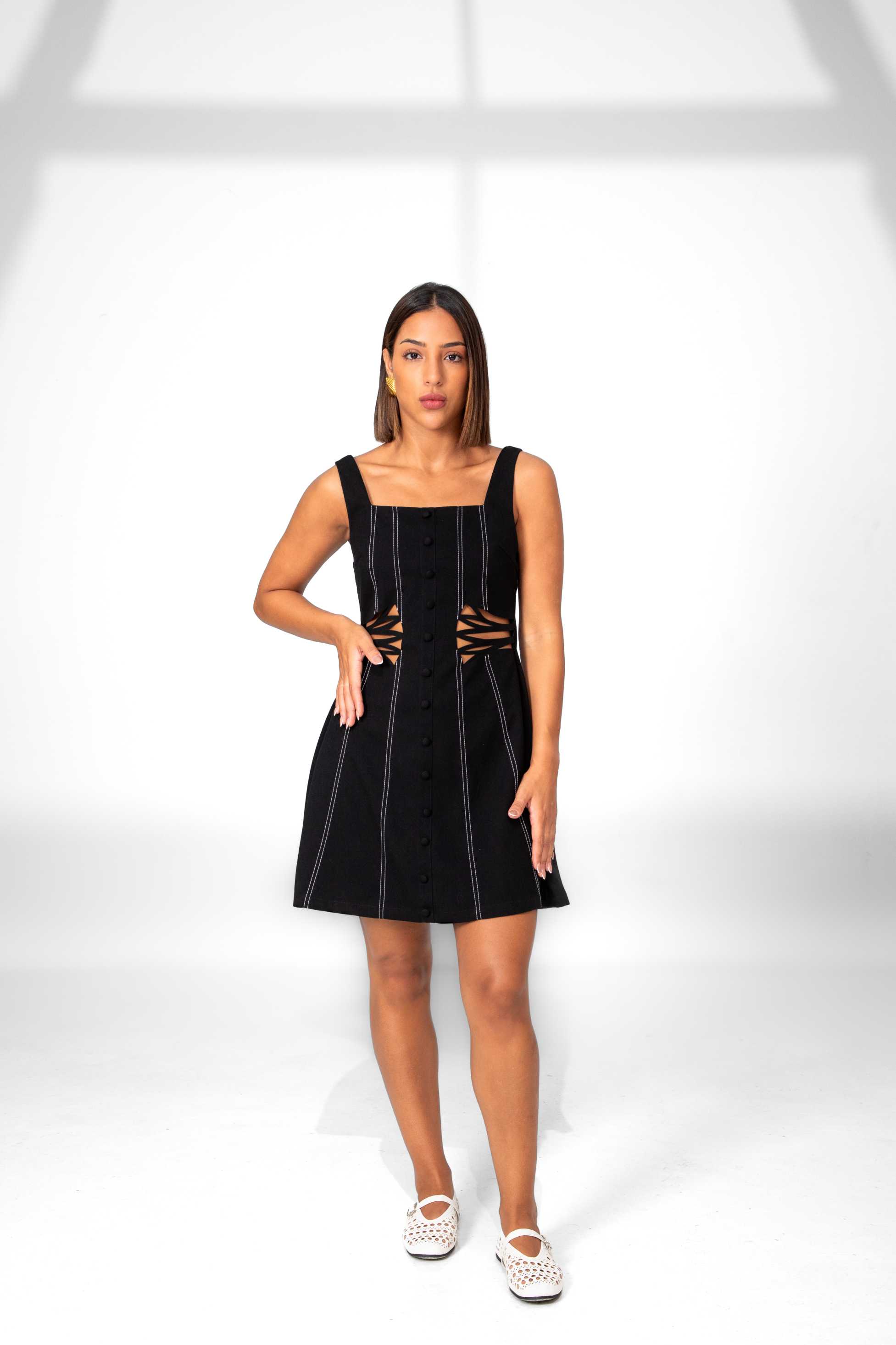 Woman wearing a black dress with cut-out details on a white background Clep