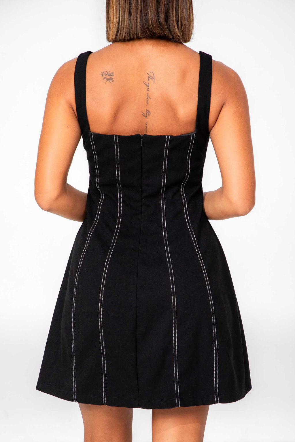 Person wearing a black pinstripe dress with a plain background Clep