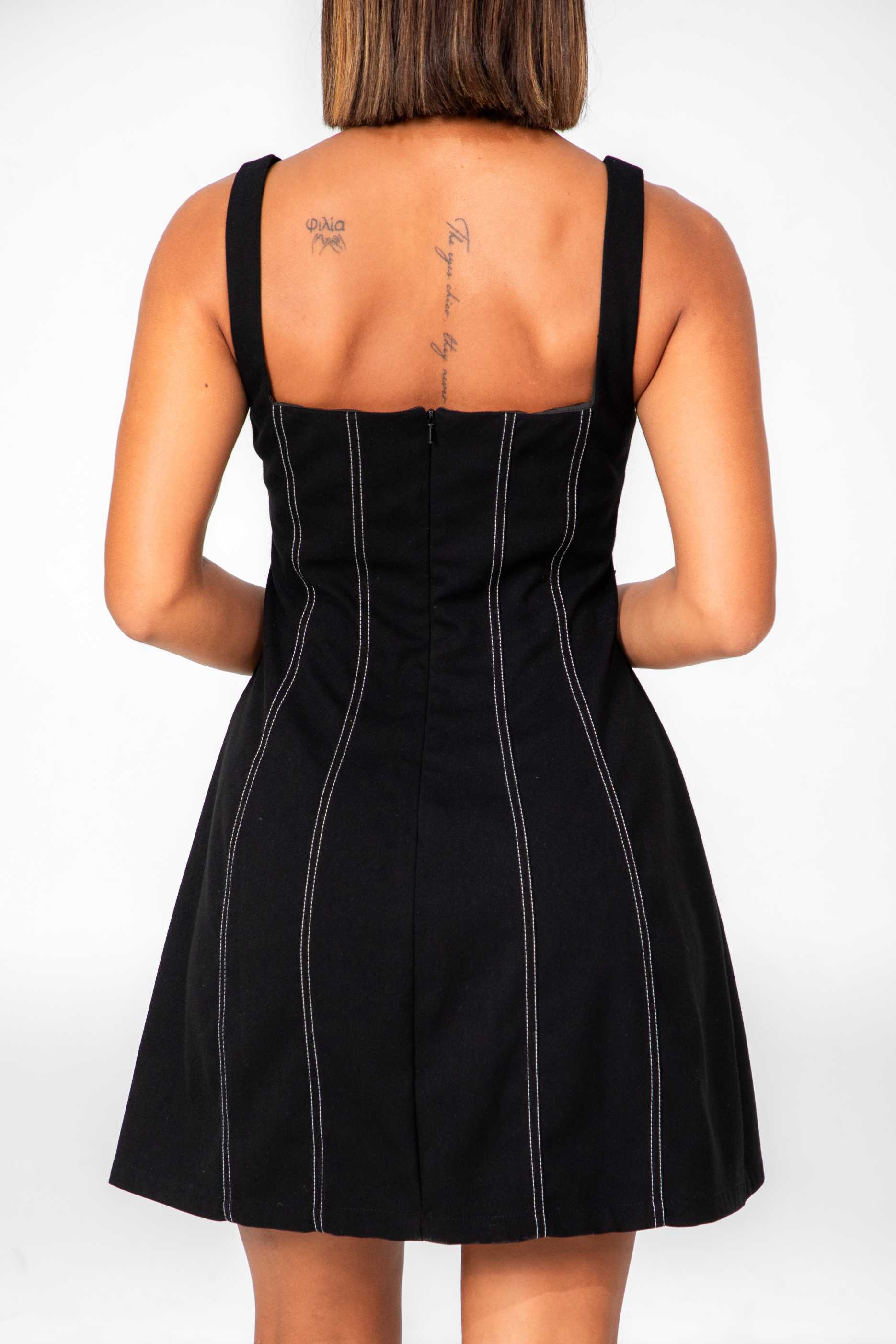 Person wearing a black pinstripe dress with a plain background Clep