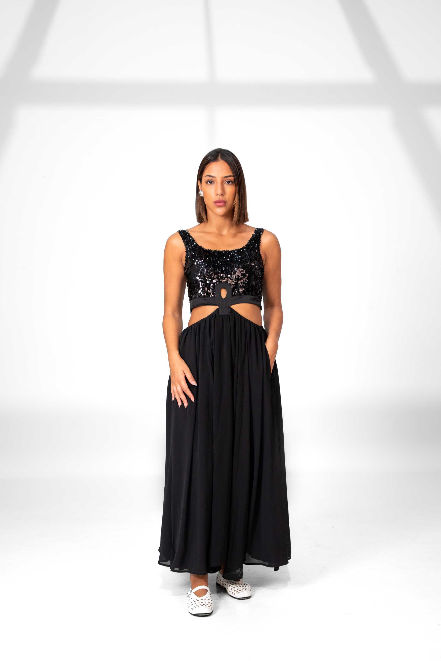 Woman wearing a black dress with cut-out design on a white background Clep