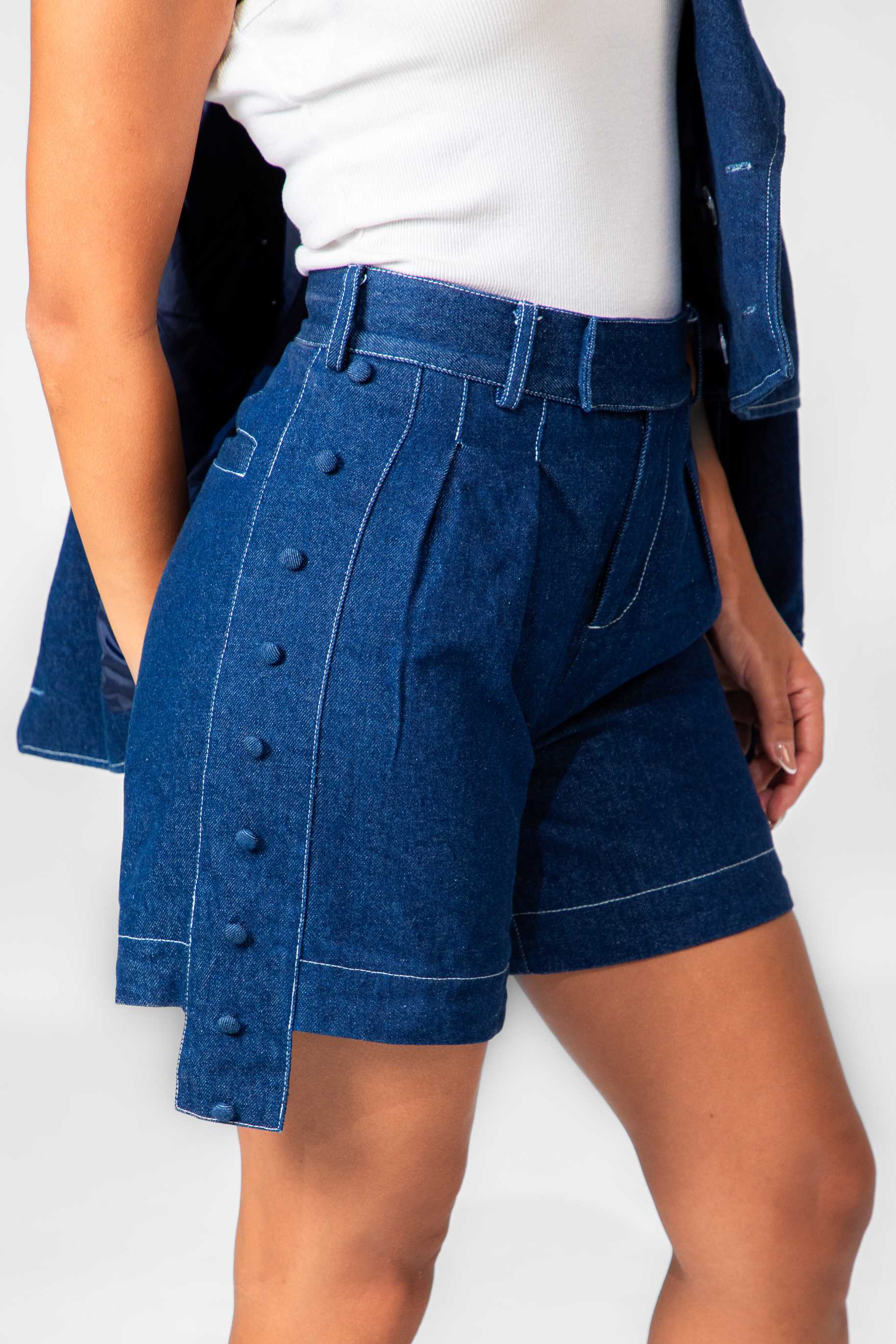 Person wearing blue denim shorts with buttons on a white background Clep