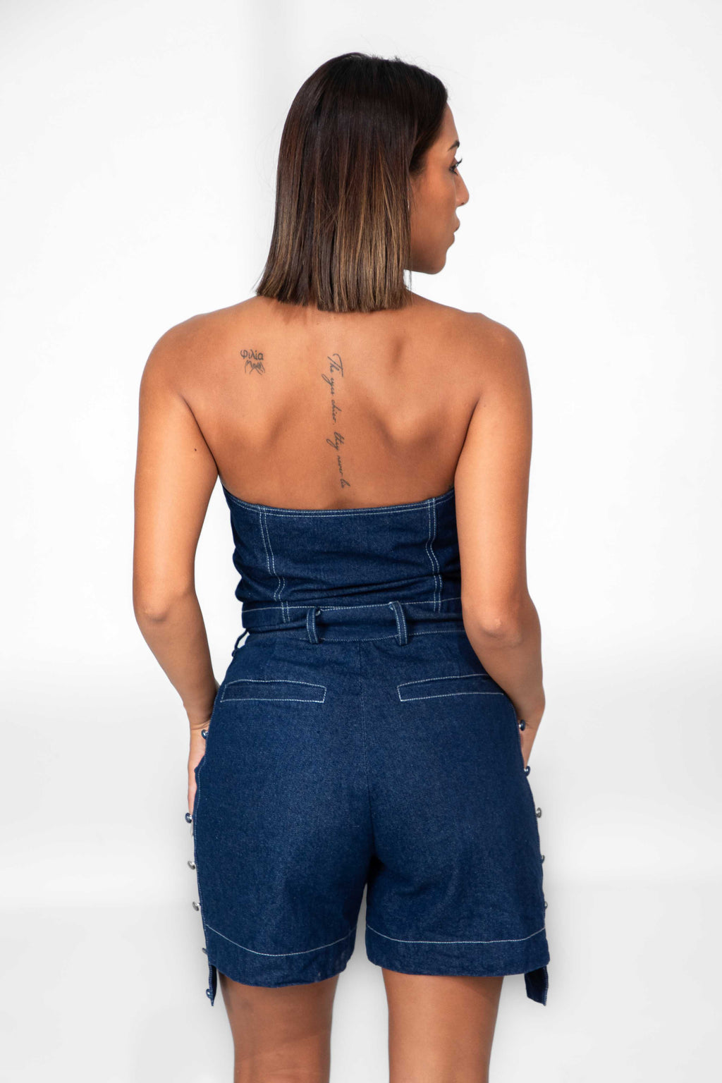 Woman wearing a strapless denim jumpsuit on a white background Clep