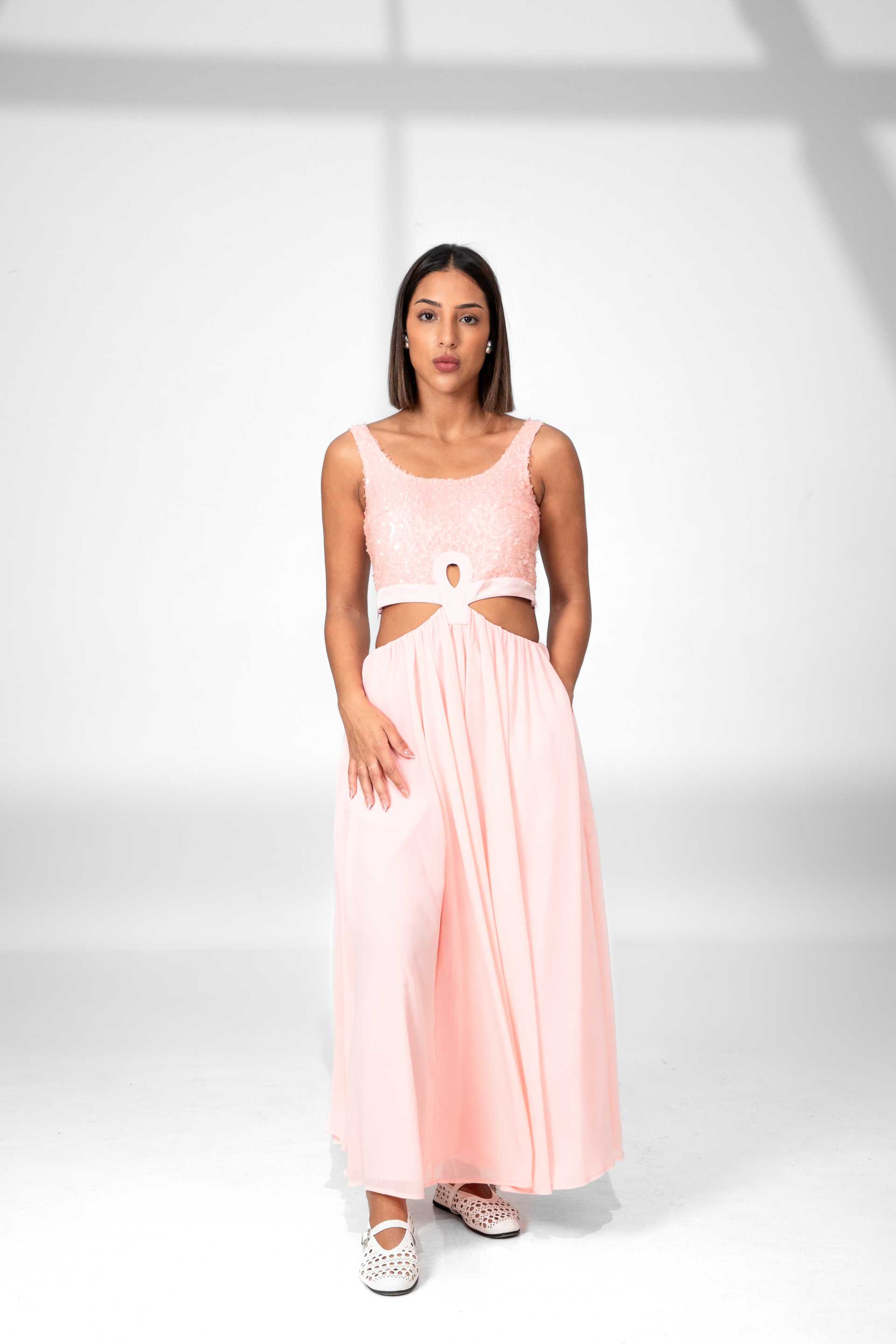Woman wearing a pink dress with cut-out design on a white background Clep