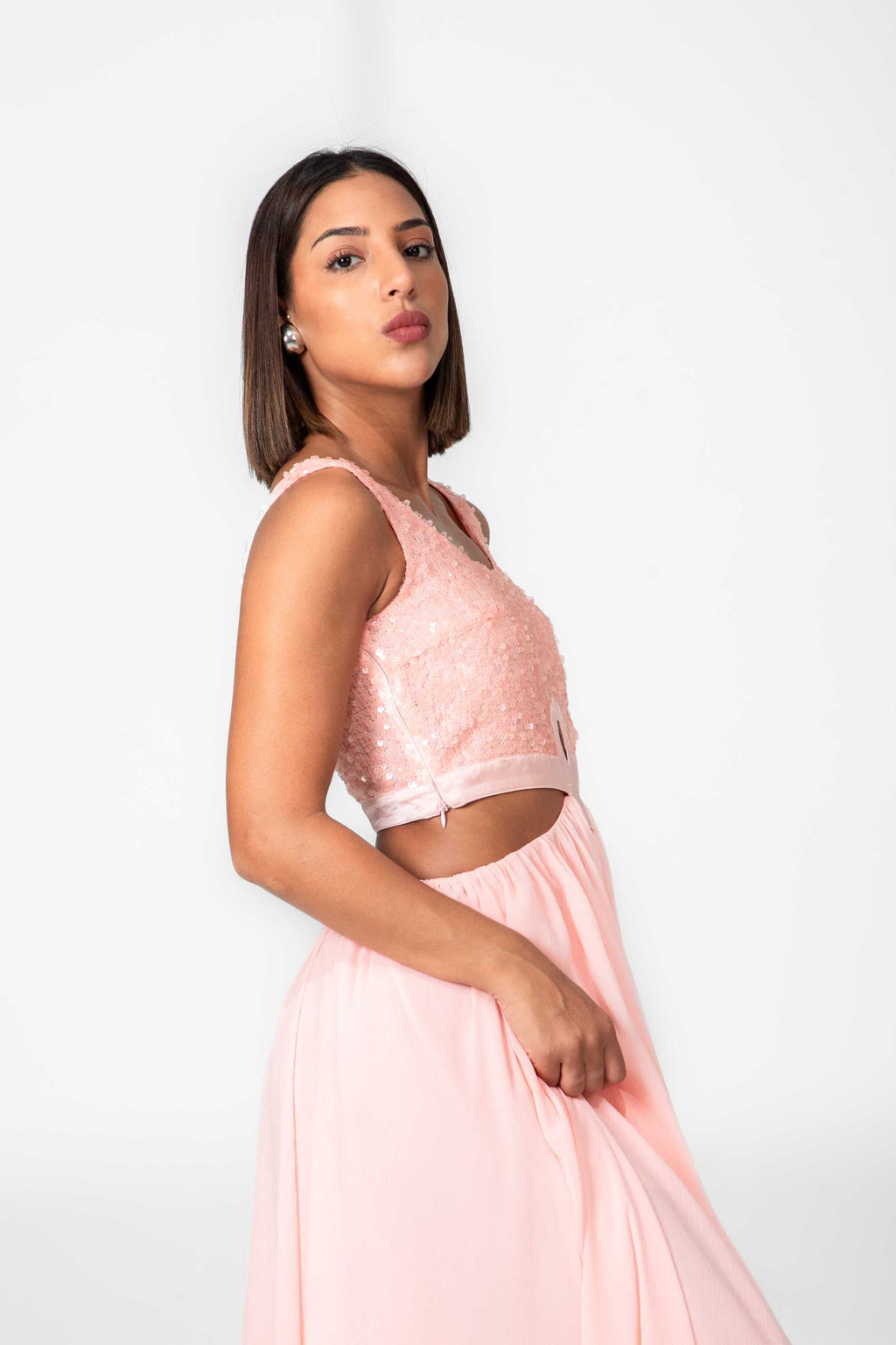 Woman wearing a pink lace top and skirt set against a white background Clep