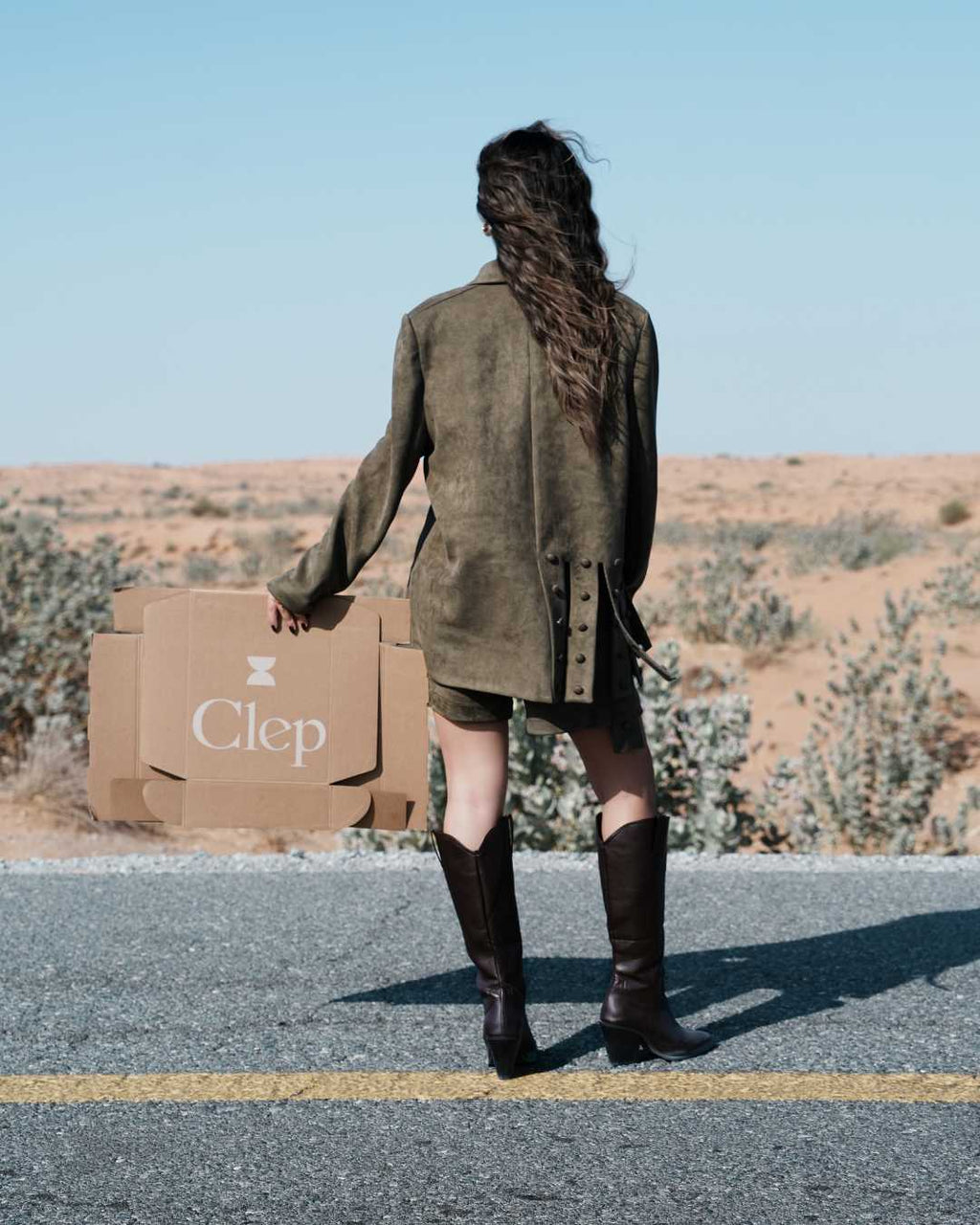 INTERVAL blazer olive suede campaign shot with clep packaging desert setting