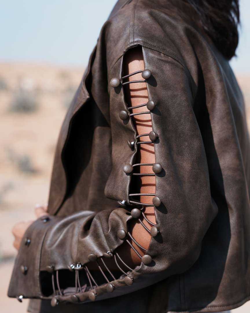 Close-up of a brown leather outfit with decorative elements against a blurred natural background Clep