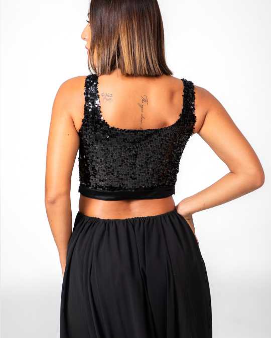 Woman wearing a black sequin top and black skirt on a white background Clep