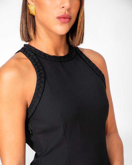 Close-up of a person wearing a black sleeveless top with a textured neckline against a white background Clep